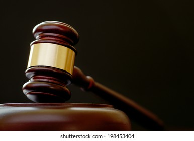 Brass bound wooden gavel resting in the upright position on a plinth, low angle view on a dark background with copyspace conceptual of justice, a judge or auctioneer