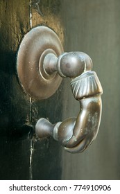 A Brass Door Knocker On A Stone Building In Beaucaire, France.  It Is In The Shape Of A Hand Holding A Ball.