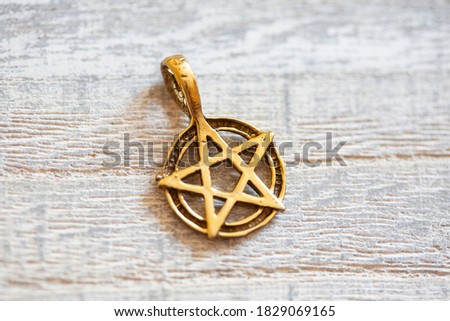 Brass golden color pentagram necklace on wooden background