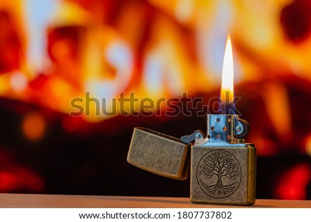 A brass lighter in front of a fireplace background.