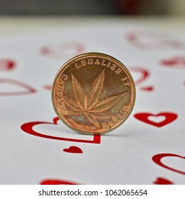 Brass physical marijuana coin in love hearts scene.