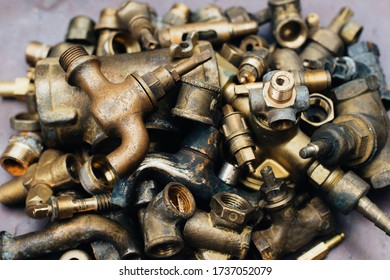 Brass Scrap Metal: Taps, Tees, Plugs And Various Plumbing Parts, Spare Parts. Against The Background Of A Copper Sheet. Close-up.