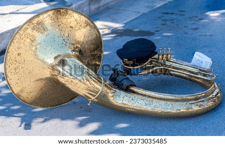 Brass tuba laying on the ground during a break whid a patronal feast