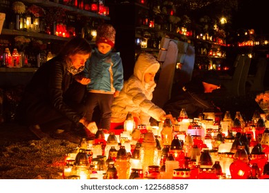 Bratislava, Slovakia. 2017/11/2. A mother with her little kids praying and lighting candles at a cemetery during the All Souls' Day. Shot at Martinsky cintorin (cemetery), Bratislava, Slovakia.