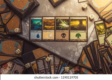 Bratislava/Slovakia - 06/13/2018: Magic the Gathering card playing game background with hand holding cards and cards and dice spread out behind