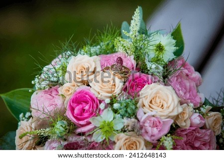 Brautstrauss mit Ringen und rosa orangenen Rosen und Grünzeug