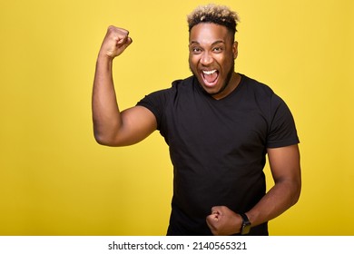 A brave African-American in a smartwatch shows his muscles and his strength with his mouth wide open. Athletic strong guy brags about his muscles in front of the camera - Powered by Shutterstock