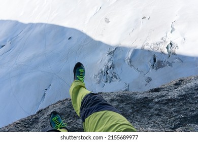 brave climber sitting on the top of rock climb near Chamonix with feet hanging on the void on Mont Blanc glacier