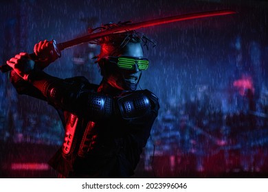 A Brave Cyberpunk Warrior Fights With A Sword In His Hands Against The Backdrop Of The Night Rainy City Of The Future. Game, Virtual Reality.