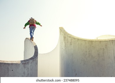 brave extreme man with backpack walking on a thin concrete wall