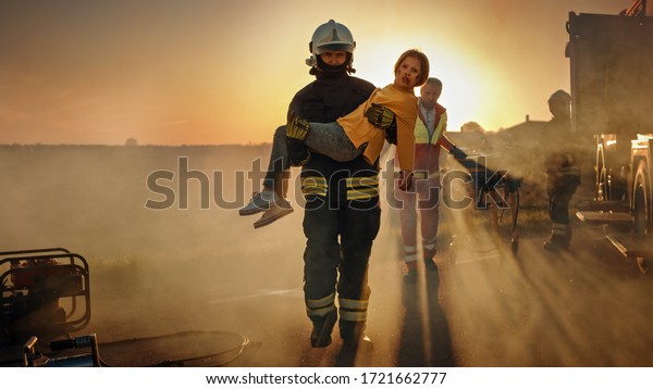 Brave Firefighter Carries Injured Young Girl to\
Safety where She Reunited with Her Loving Mother. In the Background\
Car Crash Traffic Accident Courageous Paramedics and Firemen Save\
Lives