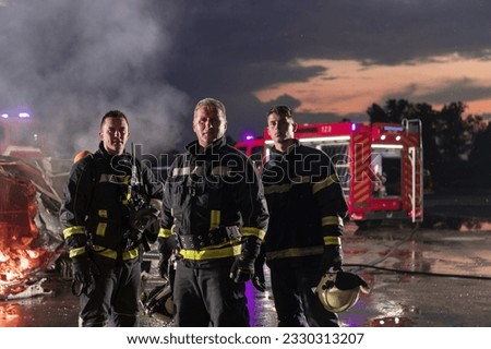 Brave Firefighters Team Walking to the Camera. In Background Paramedics and Firemen Rescue Team Fight Fire in Car Accident, Insurance and Save Peoples Lives concept.