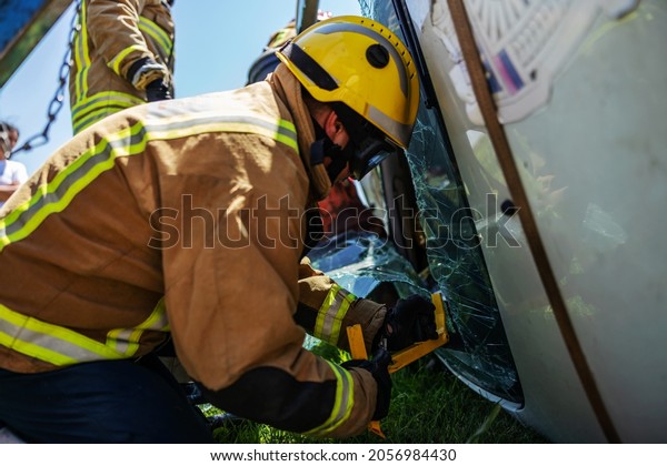 Brave fireman breaking car window and trying to\
rescue victim of car\
accident.