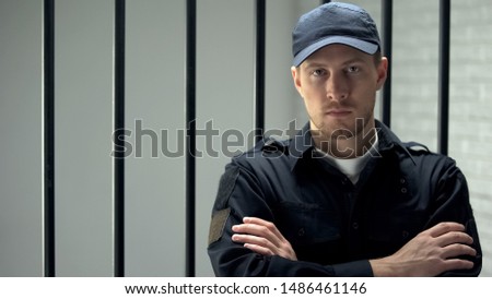 Brave jail guard looking at camera standing near cell, dangerous occupation