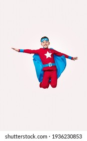 Brave Kid In Superhero Costume Jumping In Studio