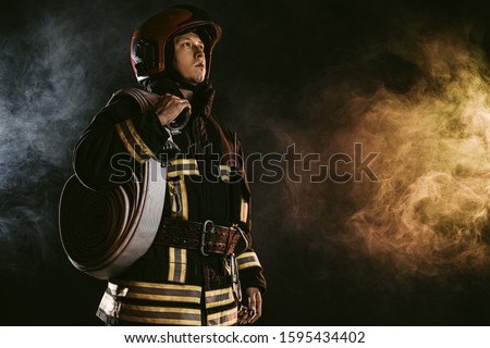 brave man fire fighter extinguishing fire, work at fire station and doing his work wearing protective uniform