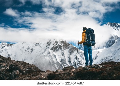 Brave tourist climb on altitude cloudy mountains. Solo traveler wearing professional backpack standing in front of high mountain  - Powered by Shutterstock