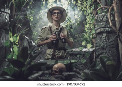 Brave woman exploring the tropical jungle and finding ancient ruins, she is holding binoculars and looking around - Powered by Shutterstock