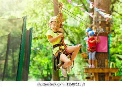 Brave young girl in helmet climbs on tree tops in amusement rope park on summer holidays, children camp - Powered by Shutterstock