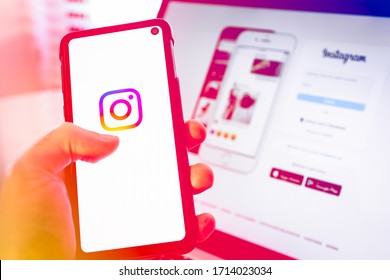 Brazil - April 2020: Hand Holding A Mobile Smart Cell Phone Device With Instagram Social Network App Logo On Screen Over A Notebook With The Log In Instagram Web Page On Display