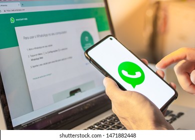 Brazil - August 05th 2019:  Hands Holding Mobile Smart Phone Device With Whatsapp Company App Logo on Screen and a Notebook with Whatsapp Web Application on Internet Browser