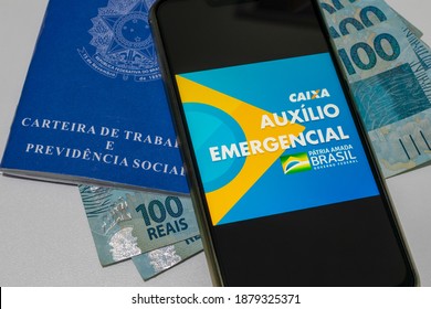 Brazil - December 20, 2020: Cell Phone With Federal Government Emergency Aid Application, Work Card And Brazilian Money. INSS