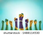 Brazil flag on people hands with clenched fists raising up for labor day national holiday celebration and stay strong for Brazilian power isolated on blue sky background (clipping path)
