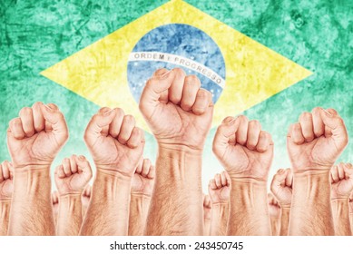 Brazil Labor movement, united workers union strike concept with male fists raised in the air fighting for their rights, Brazilian national flag in out of focus background. - Shutterstock ID 243450745