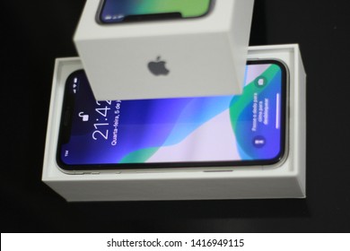 BRAZIL, MS, CAMPO GRANDE - JUNE 05, 2019: A Box Of A New IPhone X Being Opened With Wallpaper Of The New IOS 13