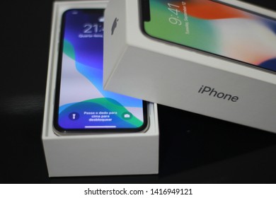 BRAZIL, MS, CAMPO GRANDE - JUNE 05, 2019: A Box Of A New IPhone X Being Opened With Wallpaper Of The New IOS 13