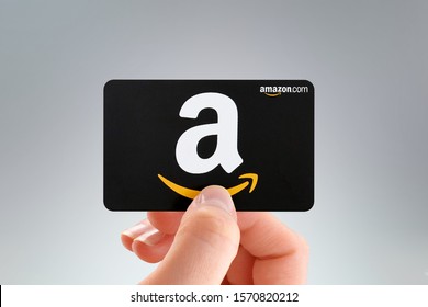 Brazil - November 26, 2019: A hand holds a $50 Amazon.com gift card a few weeks before the beginning of the holiday season in front of a white background.