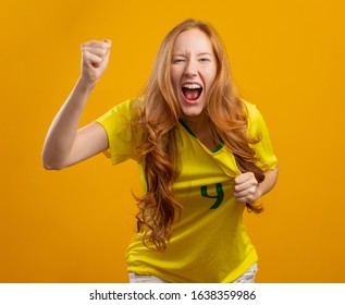 Brazil supporter. Brazilian redhead woman fan celebrating on soccer, football match on yellow background. Brazil colors. - Shutterstock ID 1638359986