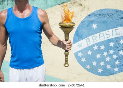 Brazilian athlete holding Olympic sport torch standing in front of a Brasil flag mural Rio de Janeiro Brazil