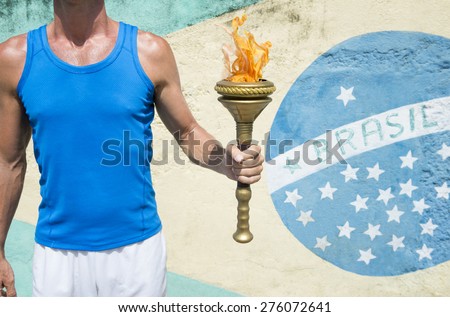 Brazilian athlete holding Olympic sport torch standing in front of a Brasil flag mural Rio de Janeiro Brazil