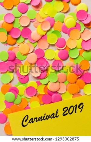 Brazilian Carnaval party background concept, space for text. Written the words: Carnival 2019. Colorful confetti spread over table. Warm colors: pink, yellow and orange. Flat lay, vertical orientation