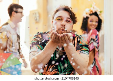 Brazilian Carnival. Young man enjoying the carnival party blowing confetti - Shutterstock ID 2104708145