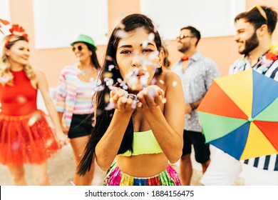 Brazilian Carnival. Young woman enjoying the carnival party blowing confetti