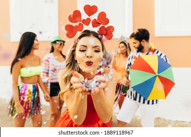 Brazilian Carnival. Young woman enjoying the carnival party blowing confetti - Powered by Shutterstock