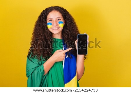 Brazilian Caucasian girl, soccer fan, holding cellphone, showing screen, cellphone app, connected world, .World Cup. Olympics.