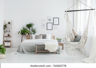 Brazilian Chair With Decorative Cushion Hanging In White Bedroom With Posters And Green Plants