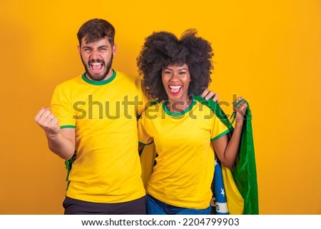 Brazilian couple fan celebrate on yellow background