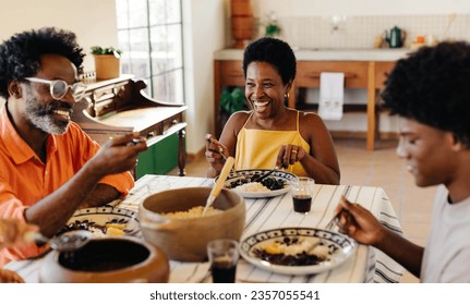 Brazilian family gathering around the table for a traditional meal, sharing laughter and smiles. The table is filled with delicious dishes and the best of Brazilian cuisine, couve and feijoada. - Powered by Shutterstock