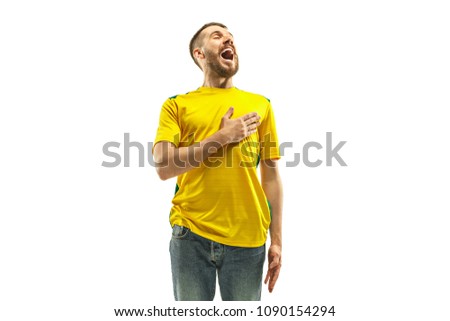 Brazilian fan celebrating on white background. The young man in soccer football uniform standing and singing a hymn at white studio. Fan, support concept. Human emotions concept.