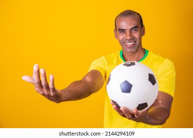 Brazilian Fan Man Holding Soccer Ball With Copy Space On Yellow Background