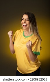 Brazilian fan. Brazilian woman fan celebrating in soccer or soccer match on yellow background. Brazil colors - Shutterstock ID 2208952065