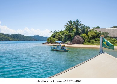 Brazilian Flag On The Top Of A Boat With Landscape Of Saco De Mamanguá, Paraty Bay, In The Background