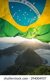 Brazilian Flag Shines Above The Golden Sunset City Skyline At Sugarloaf Mountain In Rio De Janeiro Brazil