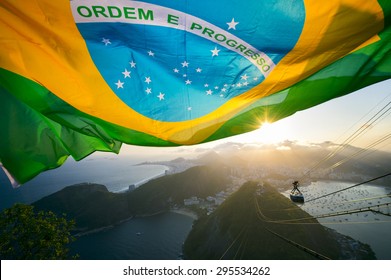 Brazilian Flag Shines Above The Golden Sunset City Skyline At Sugarloaf Pao De Acucar Mountain In Rio De Janeiro Brazil