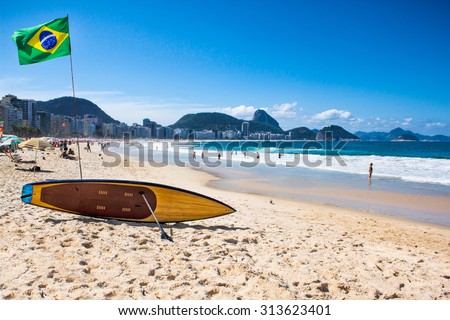 Brazilian flag and surfboard  at Copacabana Beach in Rio de Janeiro. Brazil.