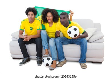 Brazilian football fans in yellow sitting on the sofa on white background